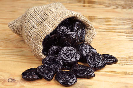 Prunes in small sack on wooden backgroundの写真素材