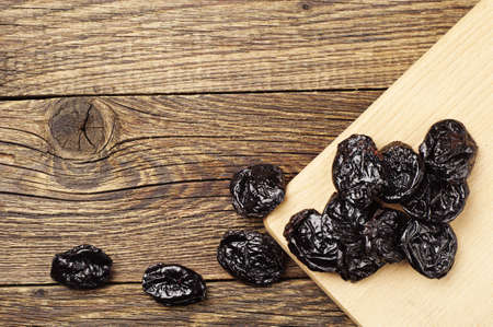 Dried plum on old wooden table closeup. Top viewの写真素材