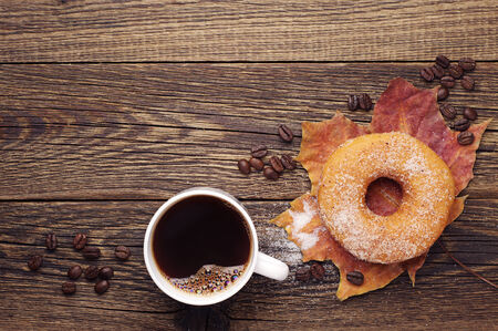Cup of hot coffee, sweet donut and autumn leaves on a wooden table. Top viewの写真素材