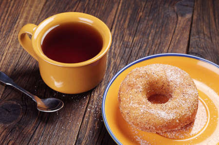 Breakfast with tasty donut and cup of hot tea on old wooden tableの写真素材