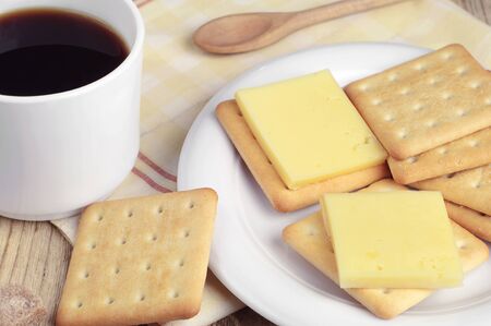 Cup of black coffee and cracker cookies with cheese and on wooden tableの写真素材