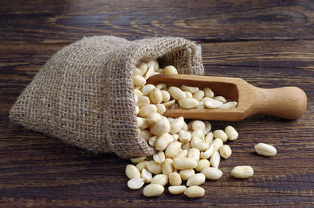 Peanuts in sack and spoon on dark wooden backgroundの写真素材