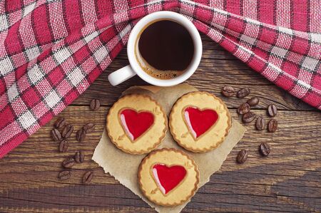 Cup of hot coffee and cookies with strawberry jam in shape of heart on rustic table, top viewの写真素材