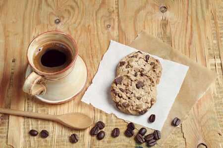 Tasty cookies and cup of hot coffee on old wooden tableの写真素材