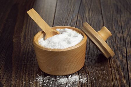Salt in wooden bowl for cooking on dark rustic table
