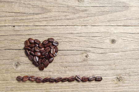 Wooden background with coffee beans in shape of hearts, top viewの写真素材