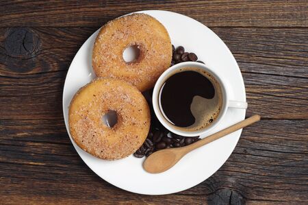Plate with donuts and cup of coffee on dark wooden table, top viewの写真素材