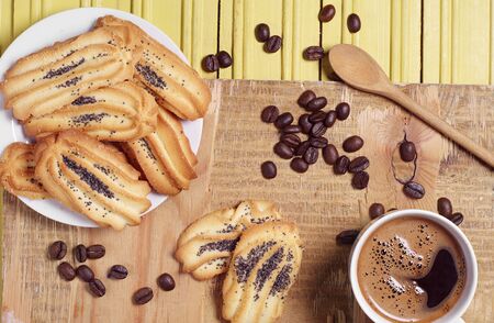 Cup of hot coffee and homemade cookies with poppy on wooden table, top viewの写真素材