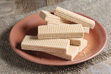 Plate with delicious wafers on a rustic wooden tableの写真素材