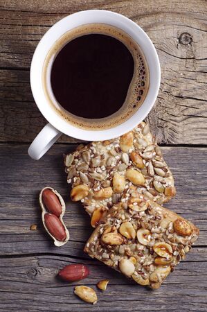 Cookies with nuts, seeds and coffee cup on old wooden table, top viewの写真素材
