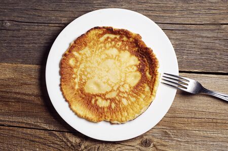 Fried pancakes in plate on old wooden table. Top view