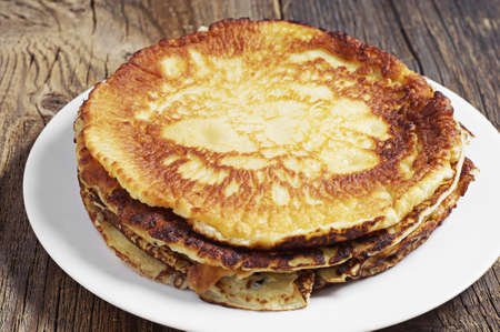 Fried pancakes in plate on dark wooden table