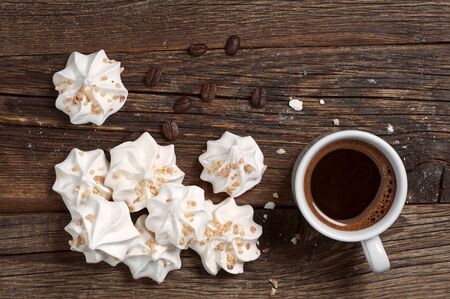 Meringue Cookies with nuts and cup of coffee on dark wooden background, top viewの写真素材