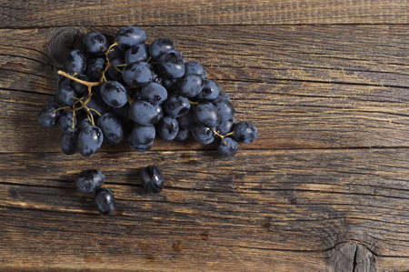 Ripe grapes on dark wooden table, top view