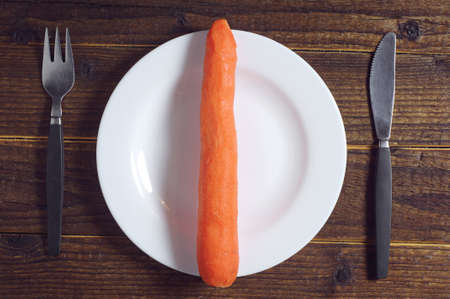 View from above on a plate with carrots, knife and fork on the tableの写真素材