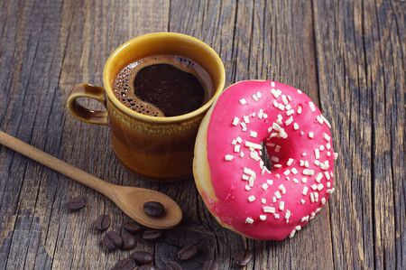 Cup of hot coffee and donut for breakfast on wooden tableの写真素材