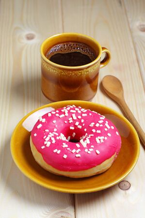 Cup of hot coffee and donut for breakfast on wooden tableの写真素材