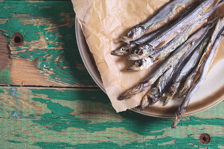 Dried salted capelin on vintage wooden background, top