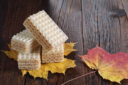 Wafers and autumn leaves on dark wooden tableの写真素材