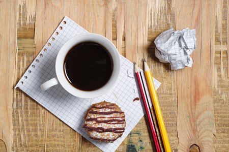 Coffee with cookie, paper and pencil on old wooden table, top viewの写真素材