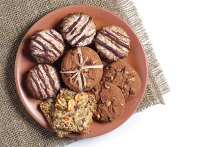 Different cookies in a plate on white background with burlap, top viewの写真素材