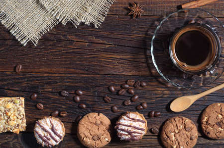 Dark wooden background with different cookies and cup of hot coffeeの写真素材