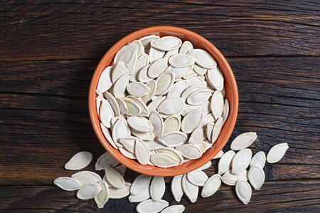 Pumpkin seeds in bowl on wooden background, top viewの写真素材