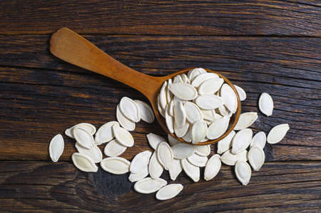 Pumpkin seeds in wooden spoon on old wooden table, top viewの写真素材