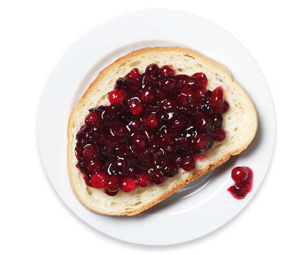 Slice of white bread with cranberry jam in plate on white background