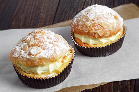 Two cake with whipped cream and almonds on table