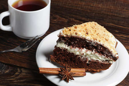 Homemade chocolate cake with whipped cream and cup of tea on dark wooden table