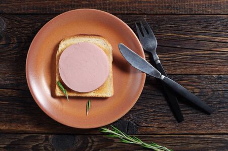 Sandwich with sausage and toasted bread on old wooden table, top viewの写真素材