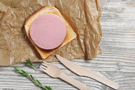 Sandwich with toasted bread and sausage on old wooden table, top viewの写真素材