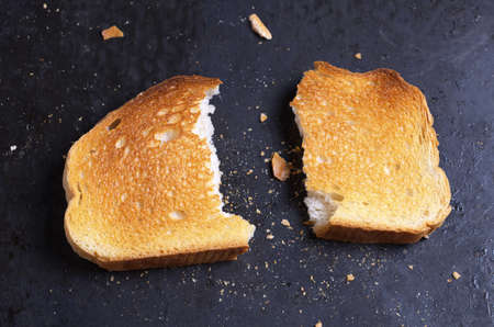 Slice of roasted white bread on black background close up. Conceptual photoの写真素材
