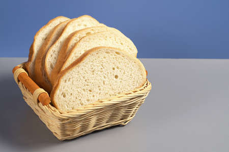 White bread in wicker wooden basket on kitchen tableの写真素材