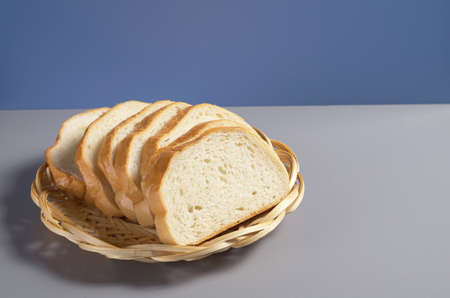 White bread in wicker wooden plate on kitchen table