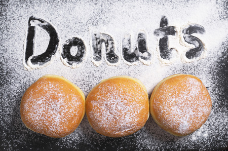 Three sweet donuts, top view. Against the backdrop the word donutsの写真素材