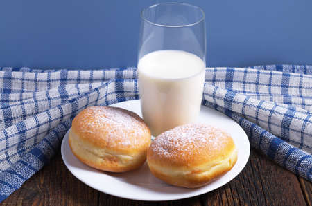 Two sweet donuts and glass of milk for breakfast on the tableの写真素材