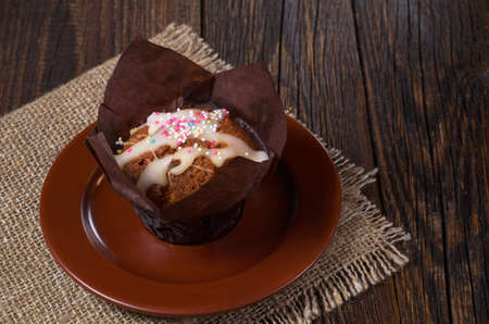 Sweet muffin in brown wax paper on rustic wooden tableの写真素材