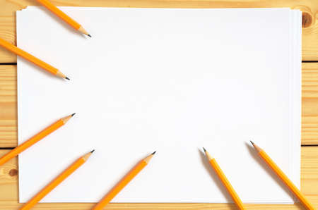 Pencils and a blank sheet of paper on wooden desk, top viewの写真素材