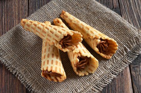 Waffle cones with sweet boiled condensed milk on rustic wooden tableの写真素材