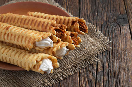 Waffle tubules with creamy in plate on dark wooden table