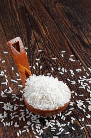 White rice in a wooden spoon on the old tableの写真素材