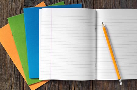 School notebooks and pencil on dark wooden table, top view
