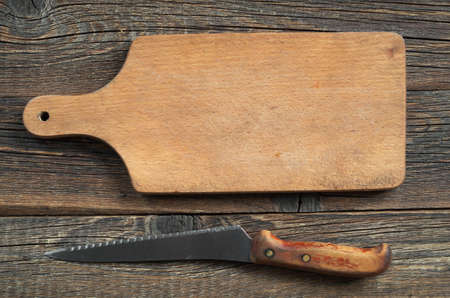 Empty cutting board and knife on old wooden table, top view. Food backgroundの写真素材