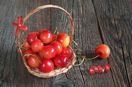 Cherries in small basket on dark wooden backgroundの写真素材