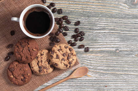 Cup of hot coffee and cookies with chocolate and nuts on rustic wooden table, top viewの写真素材