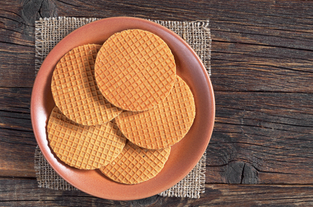 Round waffles with caramel in plate on old wooden surface, top viewの写真素材