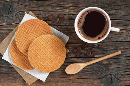 Cup of hot coffee and round waffles with caramel on old rustic table, top viewの写真素材