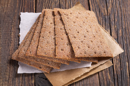 Crispy rye bread on dark wooden table closeup